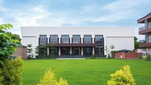 A modern building with a flat roof, large windows, and a central entrance with steps. - NANDGAON KASHI RESORT AND SPA (Varanasi)