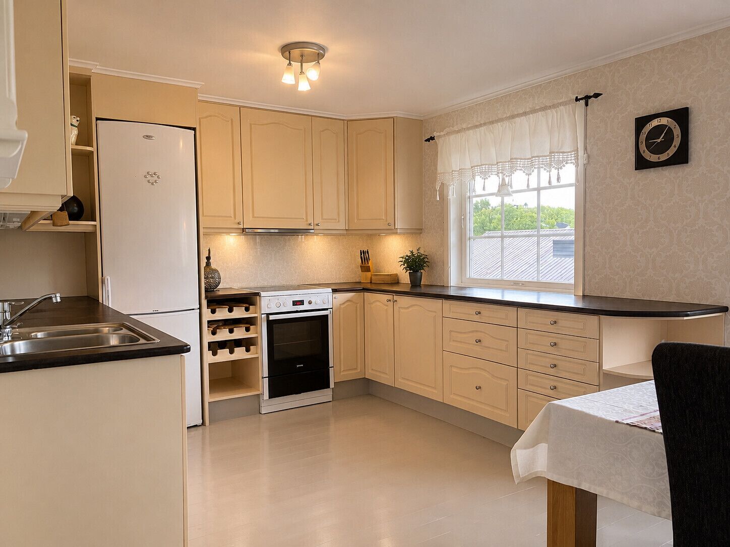 A kitchen with a built-in oven, a sink, and a window with curtains.