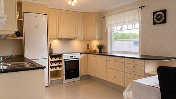 A kitchen with a built-in oven, a sink, and a window with curtains.