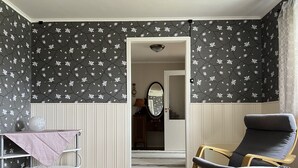 A room with a wooden floor, a chair, a small table with a pink cloth, and a wall with a floral pattern. - Spacious Home in Sudndalen at the Foot of Hallingskarvet (Hol)