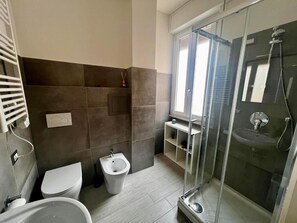 A modern bathroom with a toilet, bidet, and a glass-enclosed shower area. - Costabella Guest House (Rome)