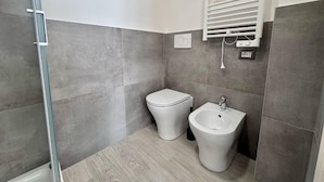 Un baño con inodoro, bidé y zona de ducha.