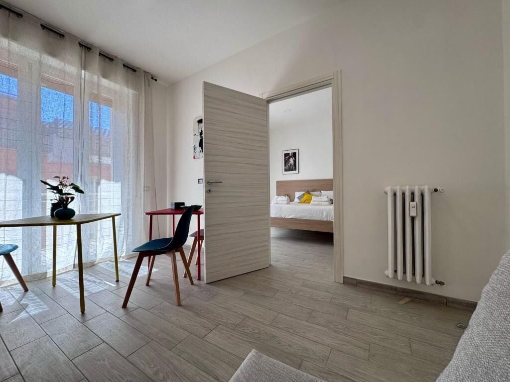 Ein modernes Zimmer mit Holzboden, einem Esstisch mit Stühlen, einem Bett mit Kopfteil und einer Heizung.