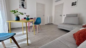 Una sala de estar moderna con un sofá, una mesa de comedor con sillas y una planta en maceta.
