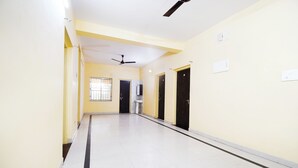A hallway with a ceiling fan, doors, and a window with bars. - Hotel O Indira Park Road Bhubaneswar (Bhubaneshwar)