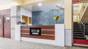 En hotellreception med en skylt som visar ordet ”HOTEL”, ett receptionsområde och en trappa.