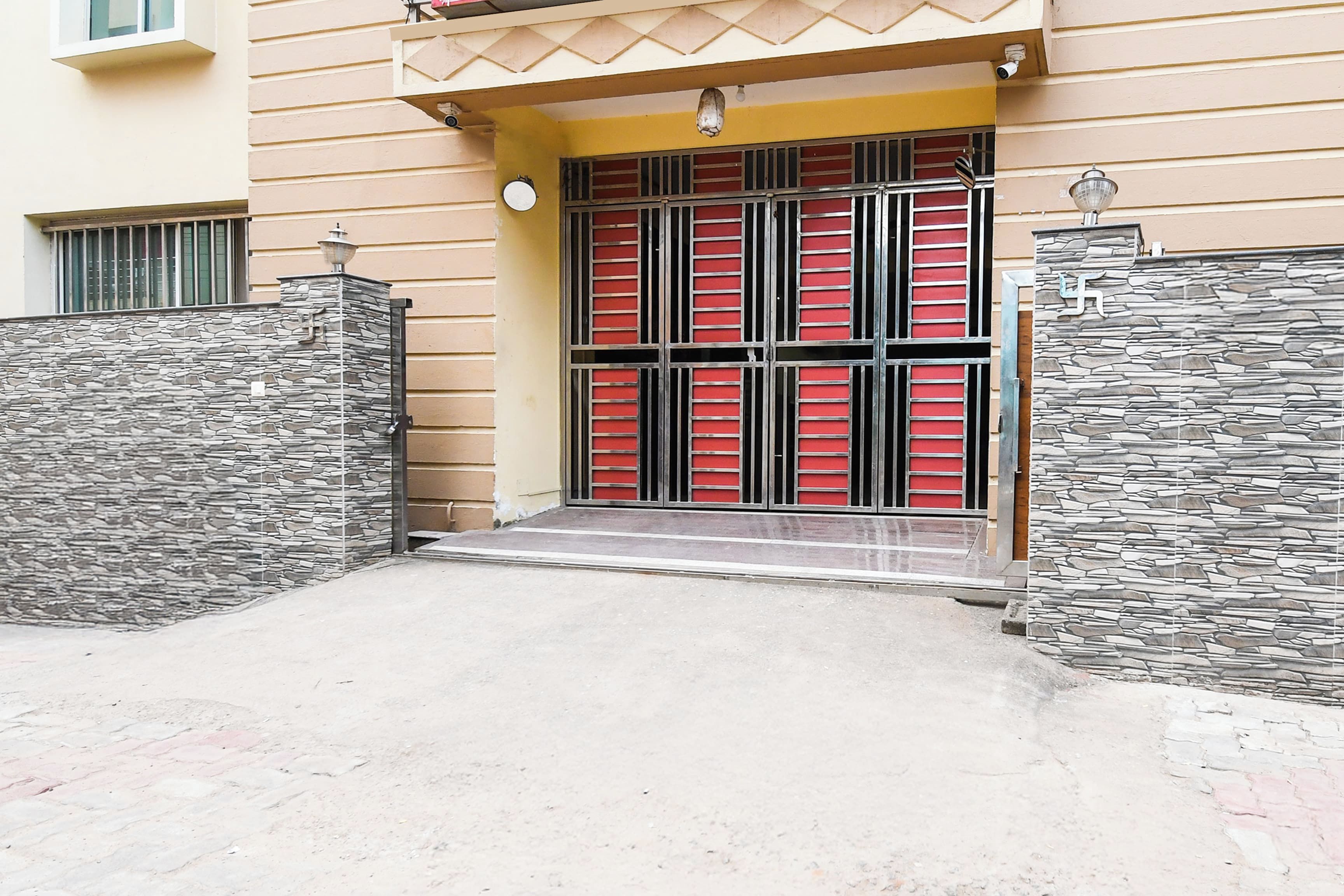 Fachada de piedra, puerta metálica y un pequeño porche en la entrada del edificio.