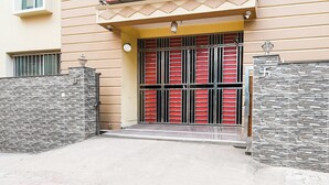 A building entrance with a stone facade, a metal gate, and a small porch area. - Hotel O Indira Park Road Bhubaneswar (Bhubaneshwar)