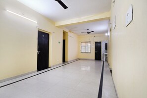 A corridor with doors, a ceiling fan, and a window with barred security.