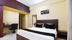A hotel room with a large bed, a desk with a chair, a small table, and a nightstand. - Hotel O Indira Park Road Bhubaneswar (Bhubaneshwar)
