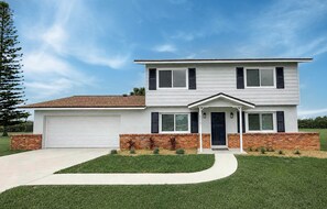 A two-story residential house with a garage, a front porch, and a brick foundation. - Launch Retreat on Merritt Island - Escape to the heart of Florida's Space Coast (Merritt Island)