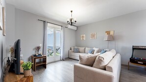 En moderne stue med sofa, fjernsyn og en lysekrone.