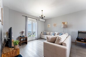 A modern living room with a sofa, a television, and a chandelier. - MalagaSuite Villa Flor de Piedra (Fuente de Piedra)