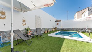 Et poolområde med en lille pool, liggestole og et bord med en flaske.