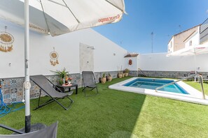 A pool area with a small pool, lounge chairs, and a table with a bottle. - MalagaSuite Villa Flor de Piedra (Fuente de Piedra)