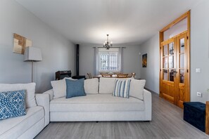 A living room with a sofa, a dining table with chairs, a fireplace, and a wooden door. - MalagaSuite Villa Flor de Piedra (Fuente de Piedra)