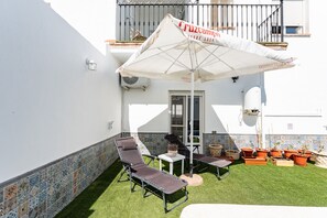 An outdoor patio with a white umbrella, two lounge chairs, a small table, and potted plants. - MalagaSuite Villa Flor de Piedra (Fuente de Piedra)