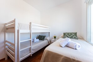 A room with two bunk beds, a single bed, a small bedside table with a lamp, and a window providing natural light. - MalagaSuite Villa Flor de Piedra (Fuente de Piedra)