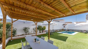 En overdækket terrasse med pool, siddepladser og plantekasser.