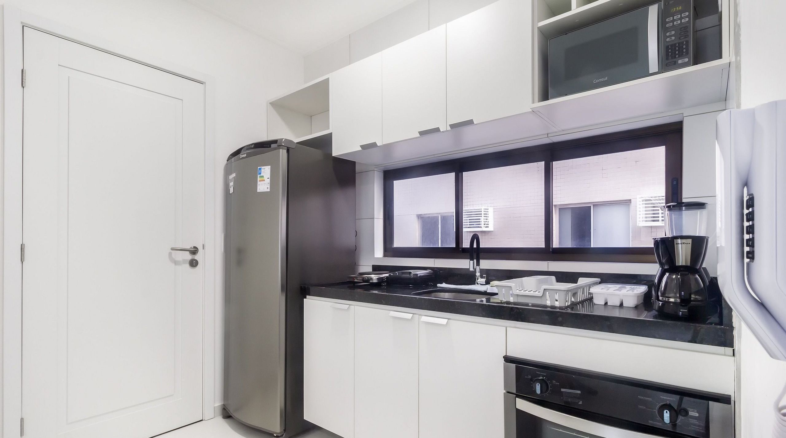 A modern kitchen with a stainless steel refrigerator, a microwave, a coffee maker, and a dishwasher.