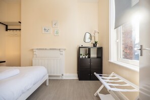 Habitació d'hotel amb llit, radiador, armari i finestra amb vistes.