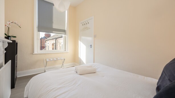 Ein Schlafzimmer mit Bett, Heizkörper, Fenster und Tür.