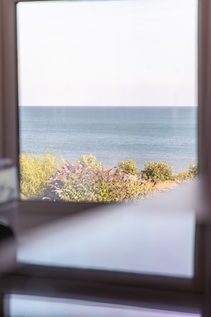 Blick auf das Meer durch ein Fenster mit Holzrahmen.