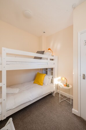 A bunk bed with a desk and a lamp, a door, and a carpeted floor. - The Blue House  - sleeps 4 guests  in 2 bedrooms (Bridlington)