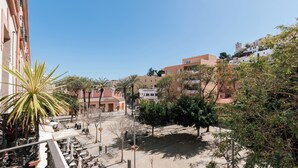 A courtyard with outdoor seating, palm trees, and buildings in the background.