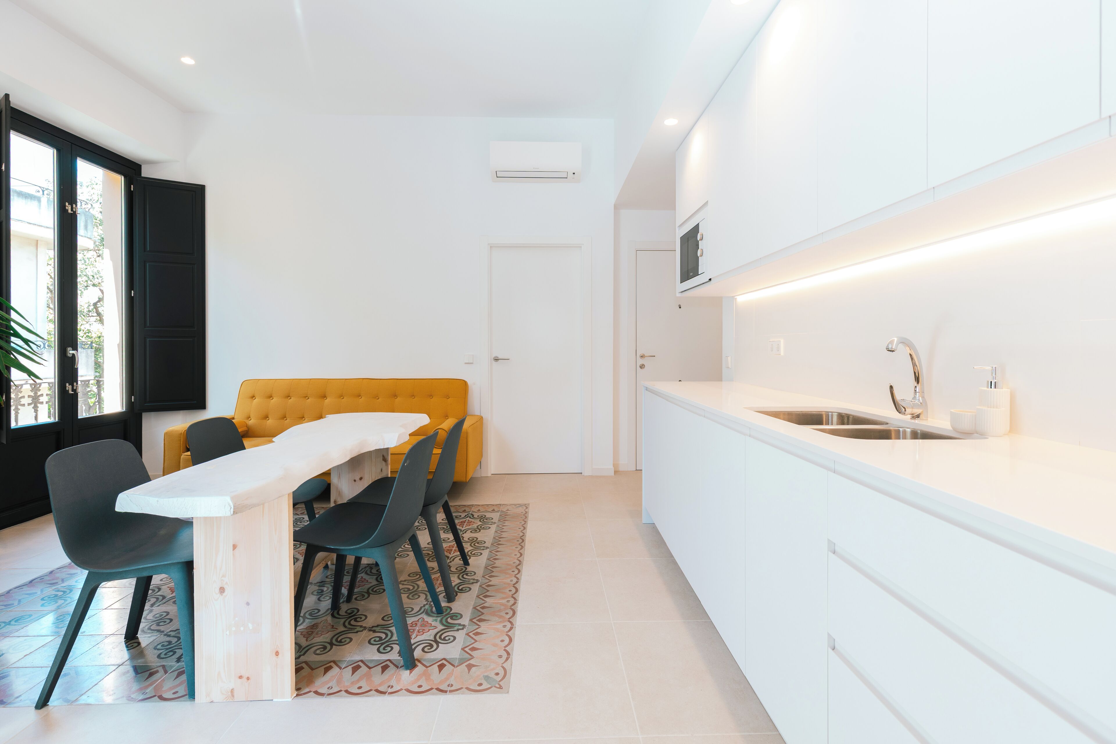 A modern kitchen with white cabinets, a built-in oven, and a stainless steel sink.
