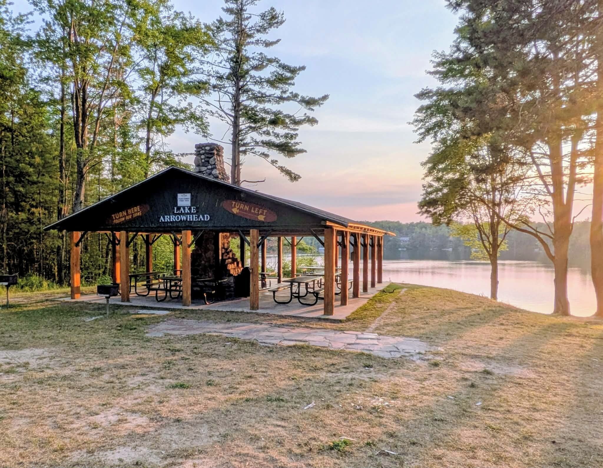 A rustic pavilion with a sign indicating directions to 'Turn Here' and 'Turn Left' for 'Lake Arrowhead'.
