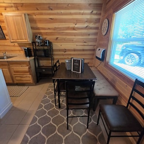A wooden cabin interior with a kitchen, dining area, and a window with blinds. - Cozy Hideaway 3-bedroom cabin in charming Gaylord (Gaylord)