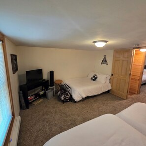 Une chambre à coucher avec un lit, un téléviseur, un radiateur, une porte en bois et une petite table.
