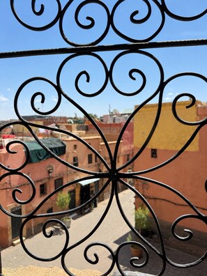 Vista a través de barandas de metal ornamentado, con edificios al fondo.