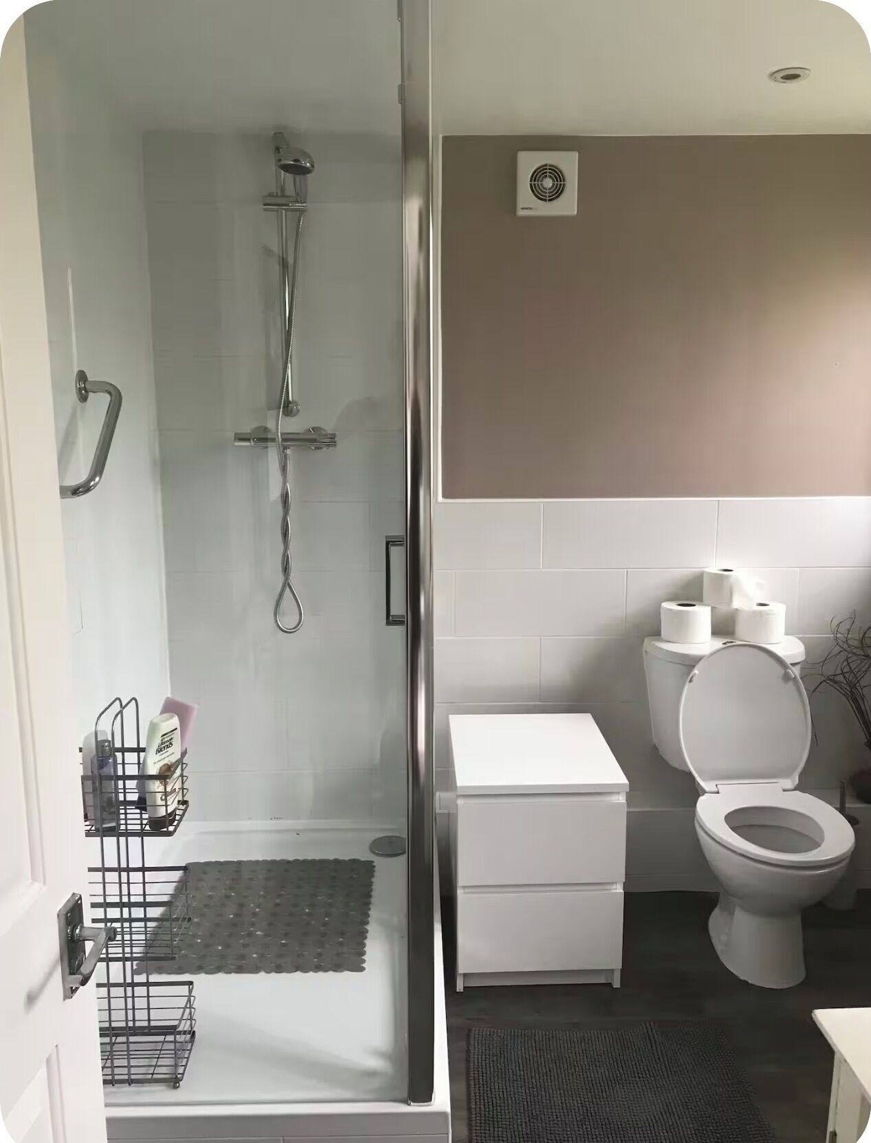 Een badkamer met douche, toilet en opslagruimte.