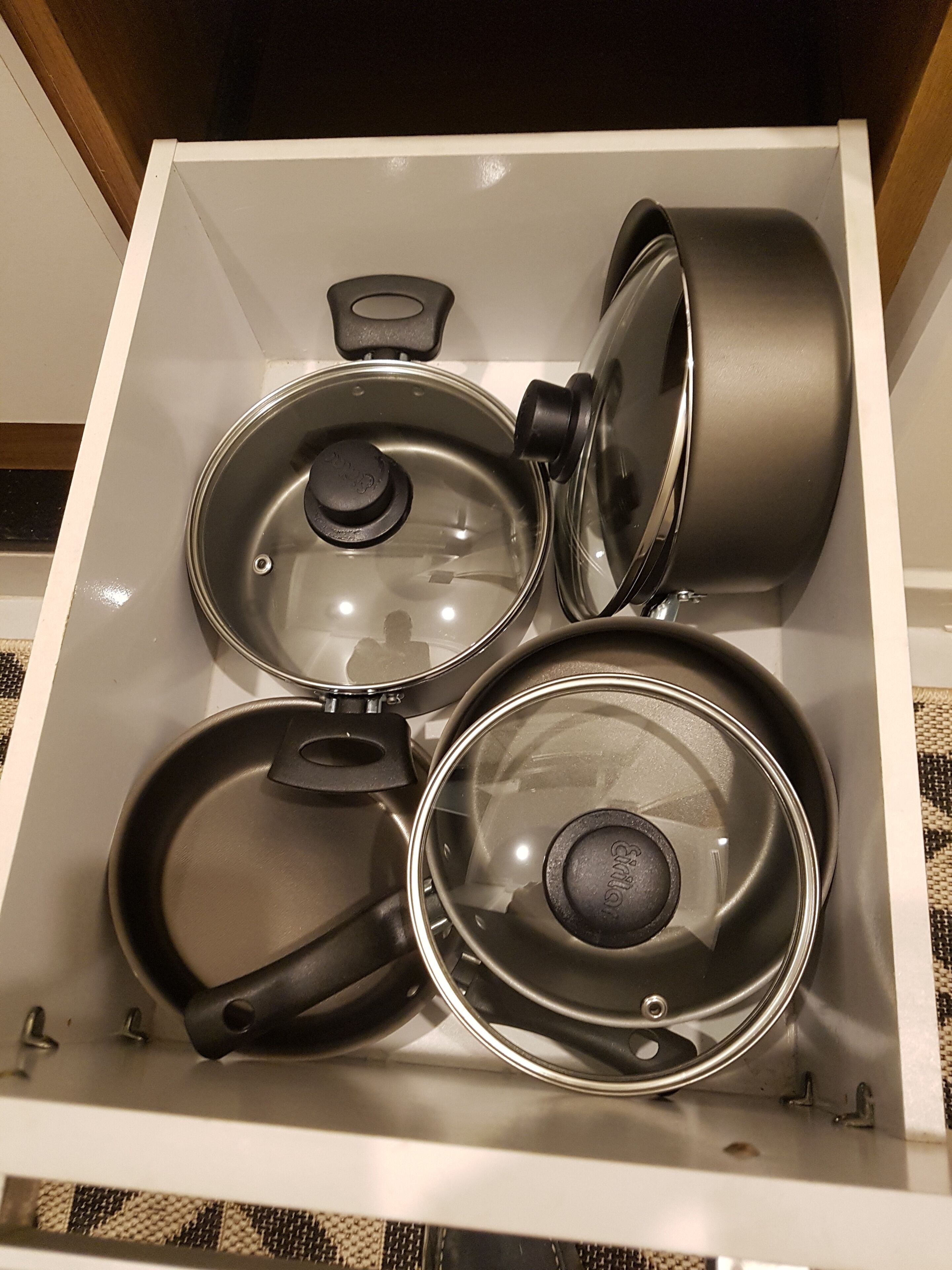 A drawer containing various kitchenware items including pots and pans.