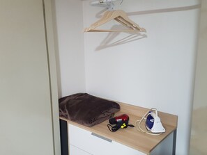 A small wooden shelf with a brown blanket, a red and black hairdryer, and a white and blue iron. - 215 Studio in Campinas/SP City Center (Campinas)