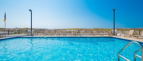 Une piscine avec des chaises longues et un drapeau.