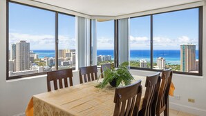 A dining area with a large table and chairs, large windows with a city and ocean view. - Stunning Panoramic Ocean Views! 2bd/2Ba PH (Honolulu)