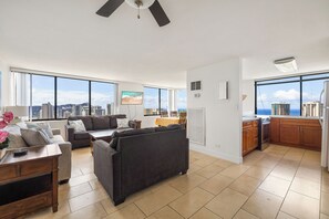 Ein geräumiger Wohnbereich mit großem Fenster, Deckenventilator und einer Küche mit Ausblick.