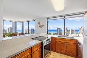 A modern kitchen with a large window, a view of the city, and a dining area with a table and chairs.