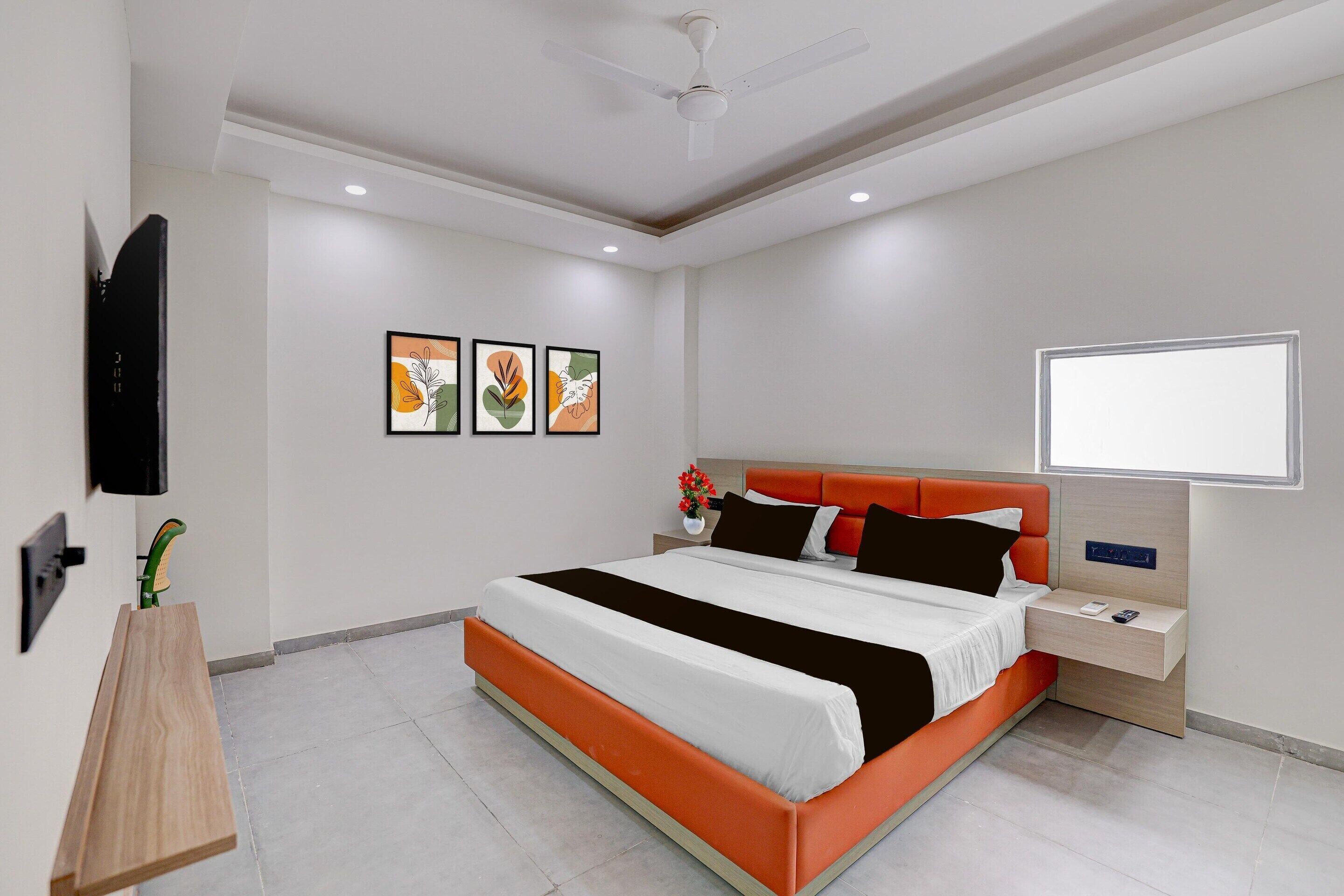 A modern hotel room with a large bed, bedside tables, a flat-screen TV, and artwork on the wall.