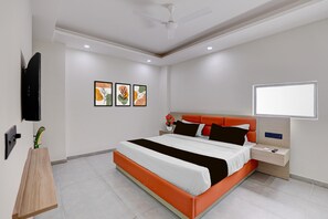 A modern hotel room with a large bed, bedside tables, a flat-screen TV, and artwork on the wall. - Classic With Balcony Townhouse Sector 52 (Gurugram)
