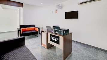 Un espace d’accueil comprenant un bureau, un canapé, un téléviseur à écran plat et un appareil de climatisation.