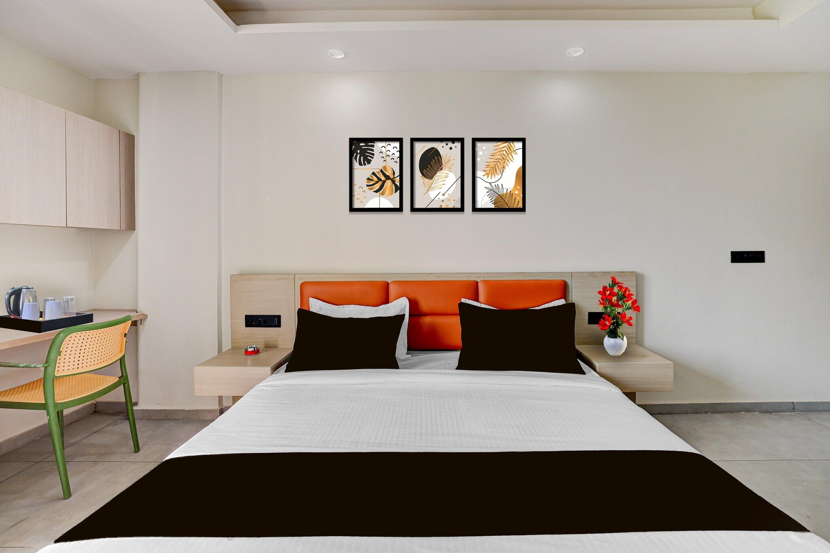 A modern bedroom with a bed, a nightstand, a chair, and a desk. There are three framed artworks on the wall.