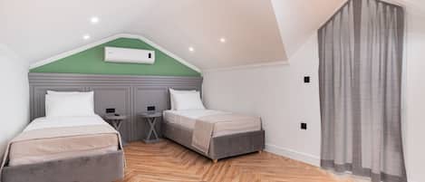 Un dormitorio con dos camas, una mesita y un aire acondicionado instalado en el techo.