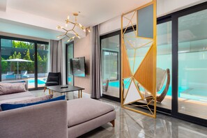 A modern living room with a sofa, a TV, and a pool view.