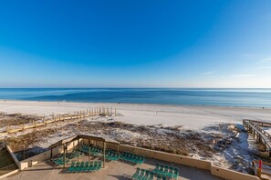 A beach view with a wooden deck and green lounge chairs. - Phoenix I 1045 2 Bedroom Condo (Orange Beach)