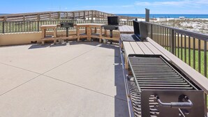 A rooftop patio with a grill, seating, and a view of the beach. - Phoenix I 1045 2 Bedroom Condo (Orange Beach)