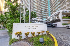 Das Schild des Ilikai Hotels mit freiem Blick auf die Architektur des Gebäudes und die umliegende Bepflanzung.